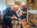 George Cunningham tries out his newfound carpentry skills under the watchful eye of tutor Tom Roche